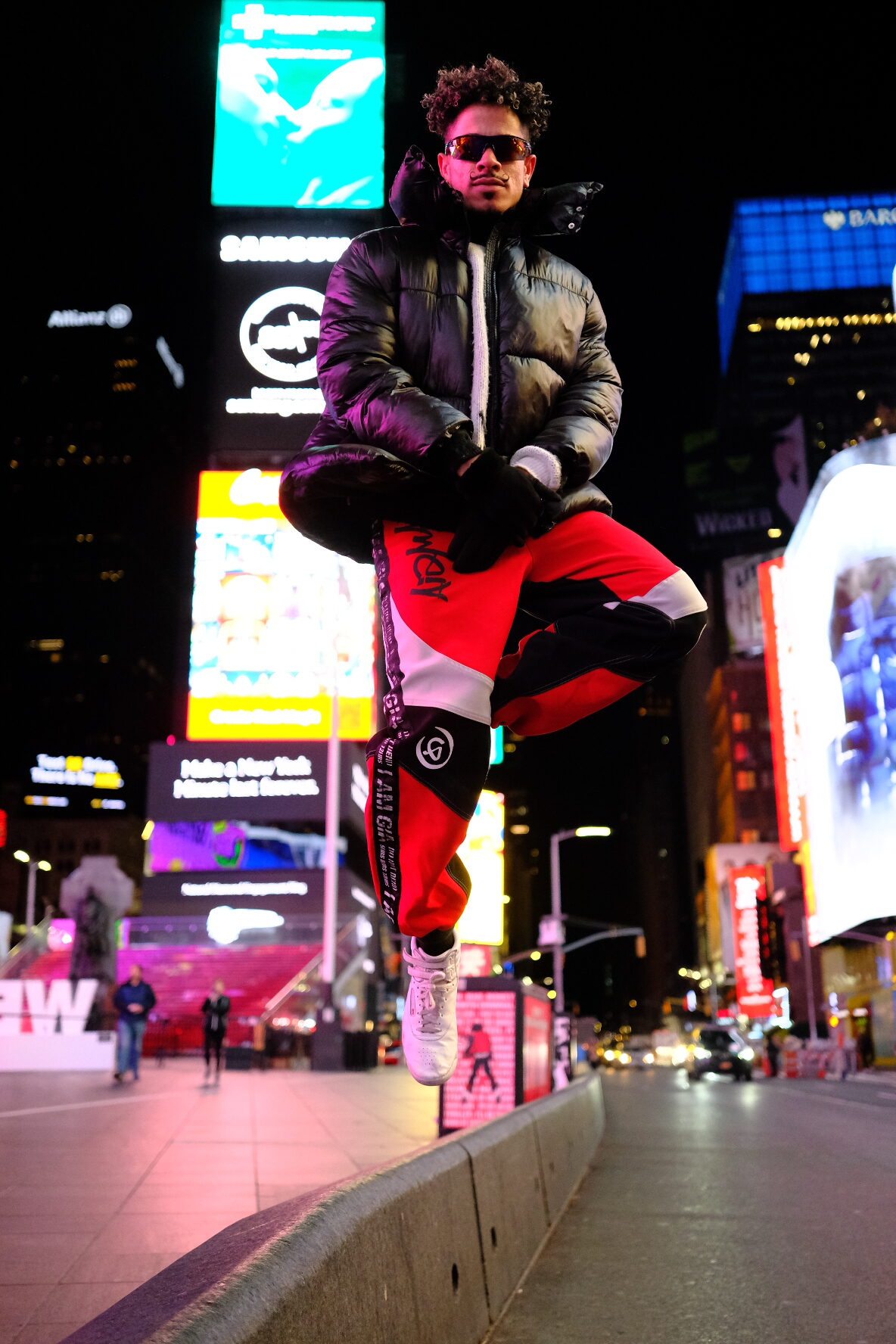 A dancer caught mid-jump above the lights of Times Square at night